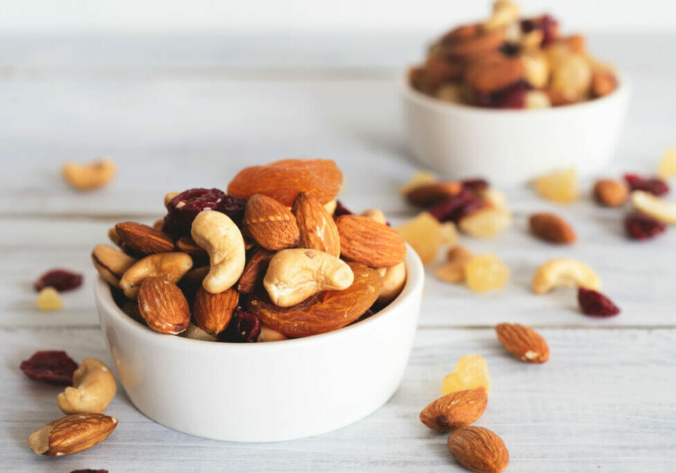 mixed nuts and dried fruit in wooden bowl on wooden table top view. Walnut, pistachio, almond, hazelnut, cashews, apricot, berry, banana, pineapple, Healthy food and snack