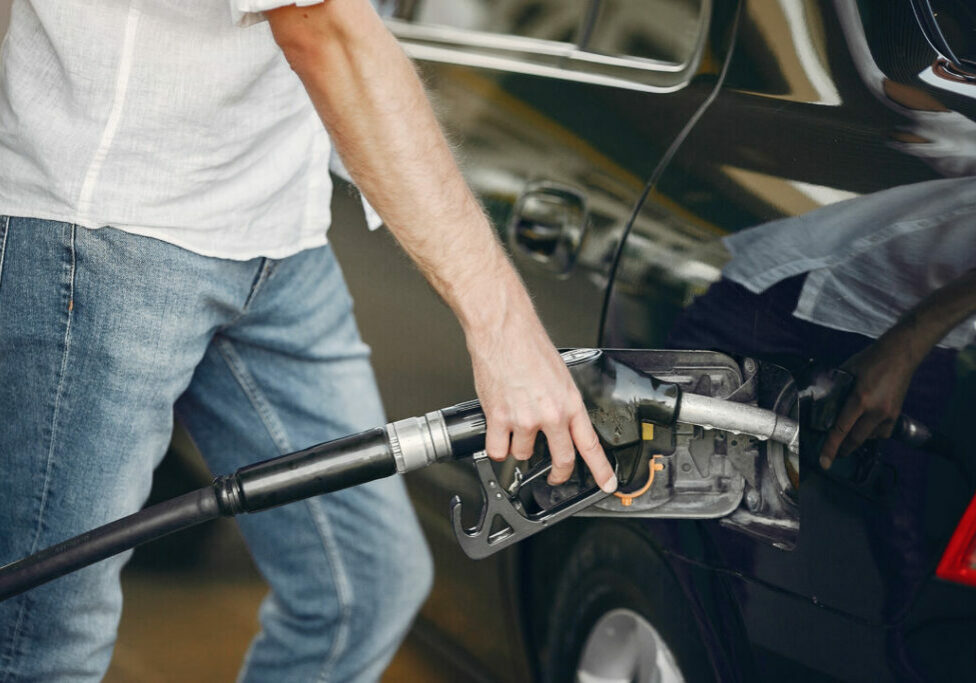 Man on a gas station. Guy refuelong a car. Male in a white shirt.