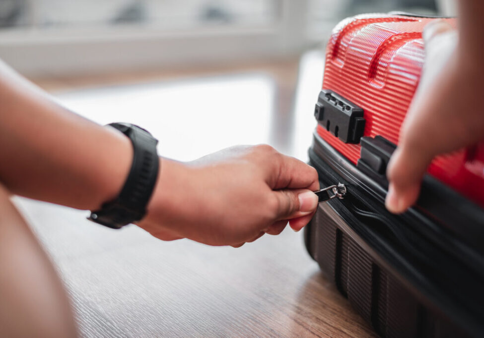 Close-up of  traveler man have finished packing and is locking them. Man is preparing clothes in suitcases. Travel, holiday and vacation concept.