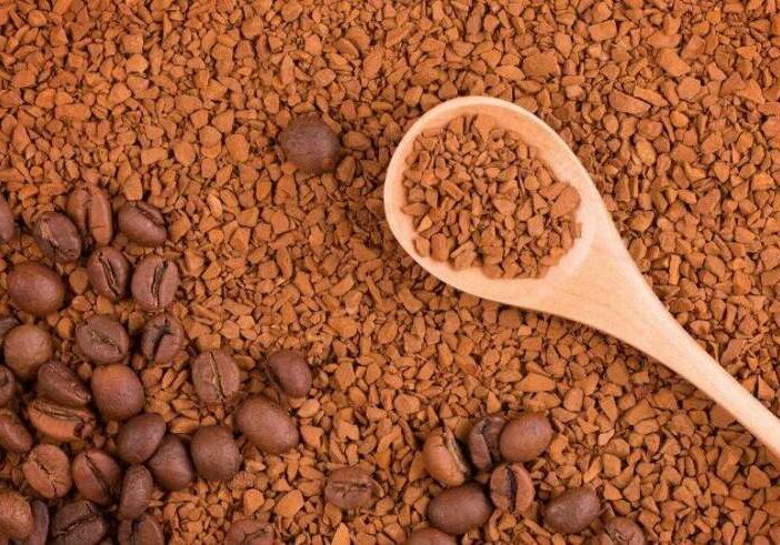 Instant coffee in a wooden spoon. Two states of coffee beans and soluble granules. Instant coffee in granules and whole coffee beans. (Instant coffee in a wooden spoon. Two states of coffee beans and soluble granules. Instant coffee in granules and wh