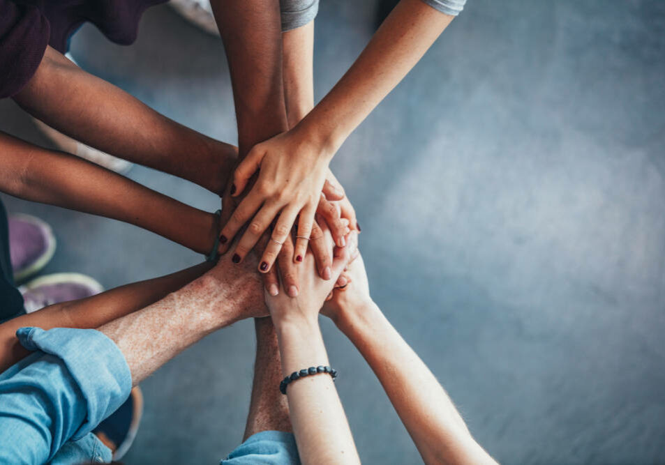 Close up top view of young people putting their hands together. Friends with stack of hands showing unity.