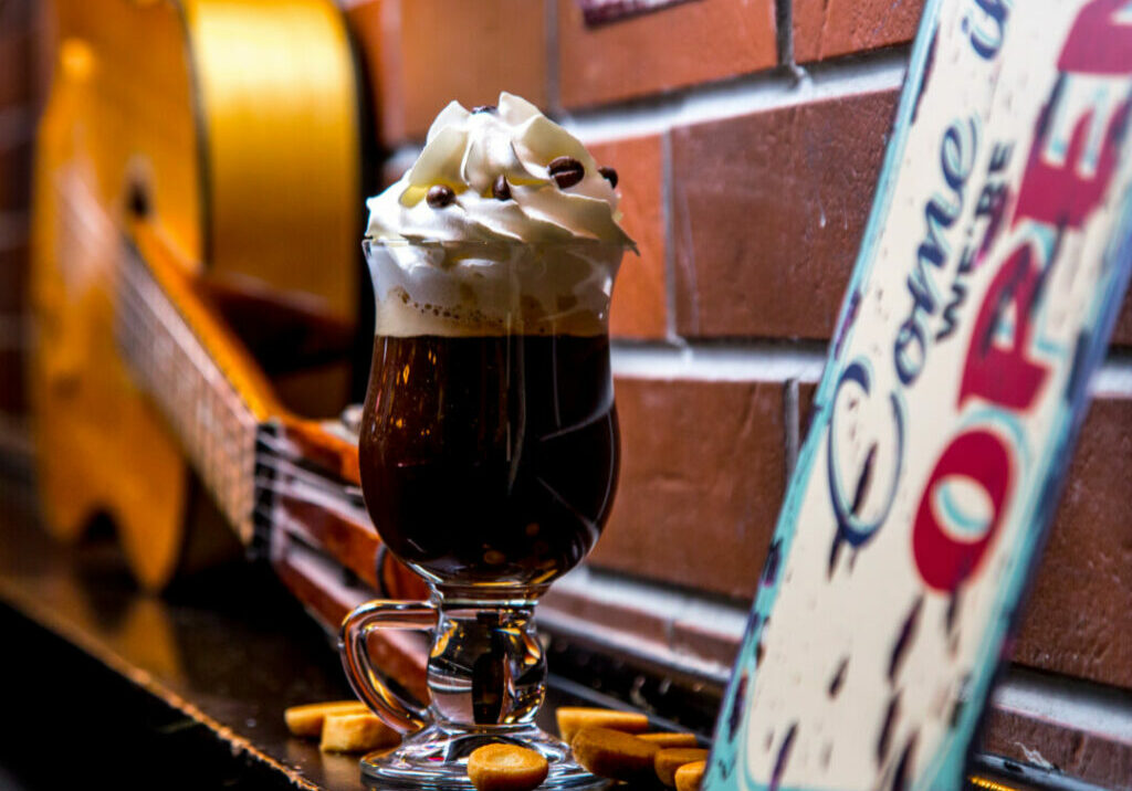 side view of irish coffee with whipped cream decorated with chocolate chips on brick wall background